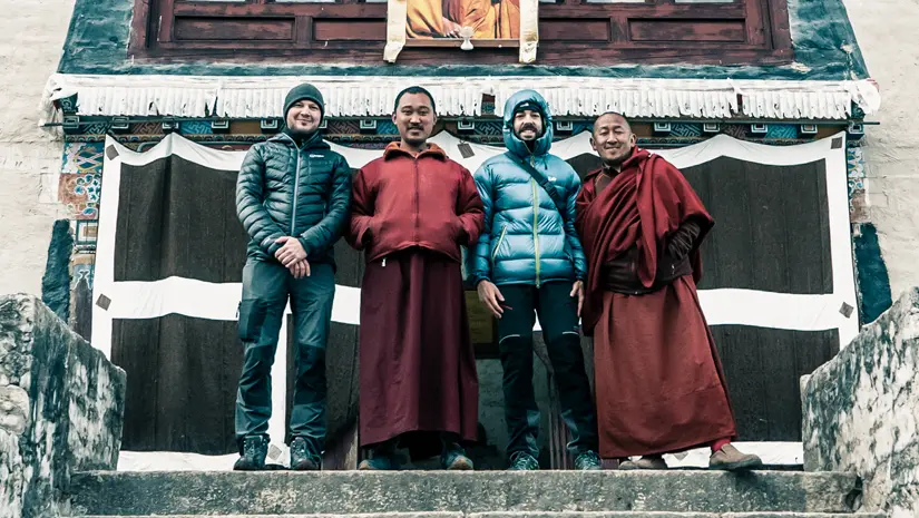 Two monks and two travelers in front of the Buddhist monastery in Tengboche