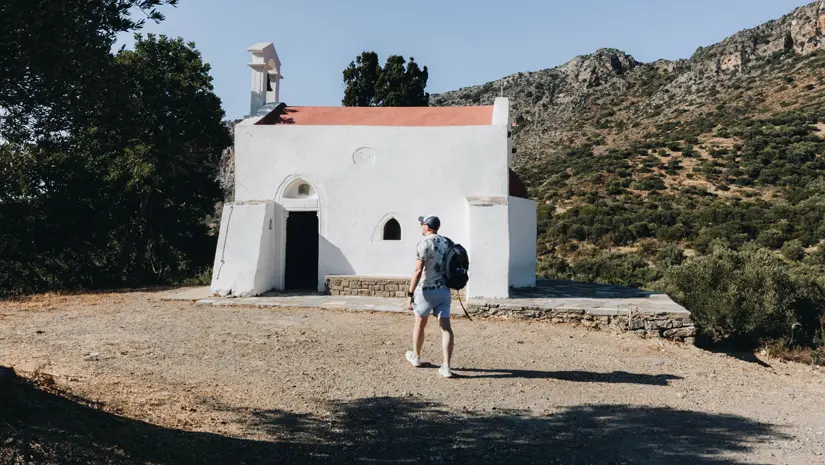 Traveler overcoming fear of solo travel in front of a small church in Crete.