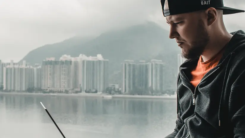 Content creator sitting in front of a large window at a high-level hotel room in Hong Kong, overlooking the cityscape.